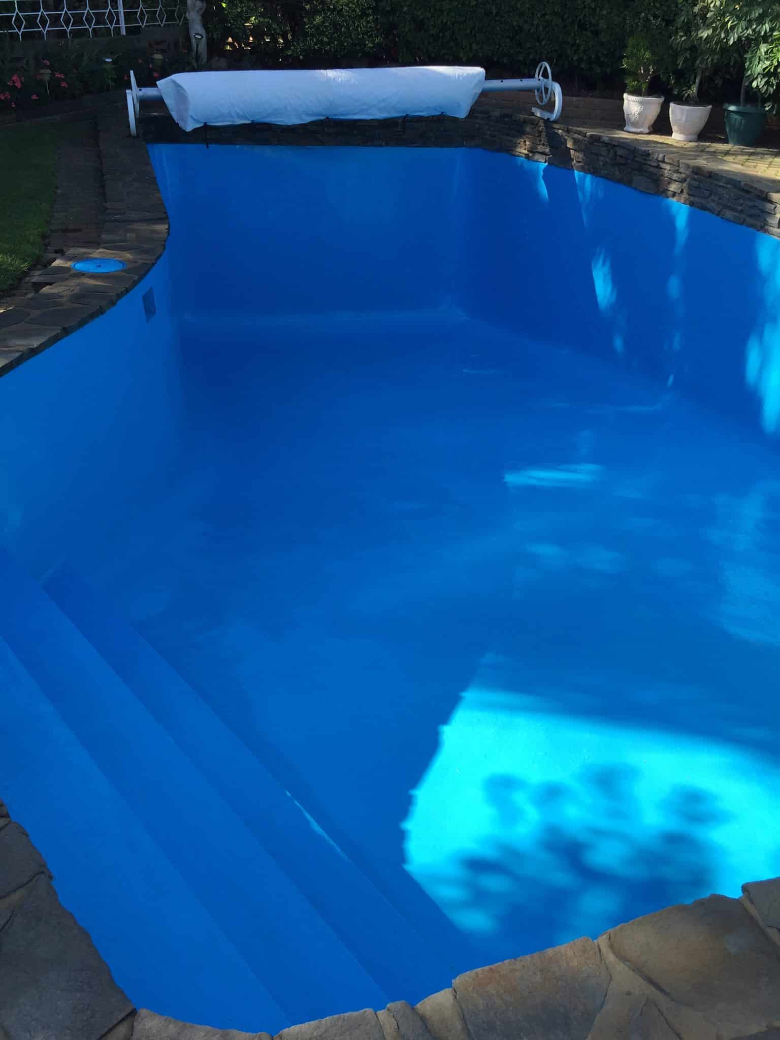 Adelaide concrete pool after Blue Revive restoration — deep blue water, fresh surface, stone coping, garden surrounds